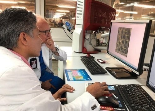 Dos hombres sentados frente a un computador que proyecta en la imagen contenidos relacionados con ingeniería administrativa