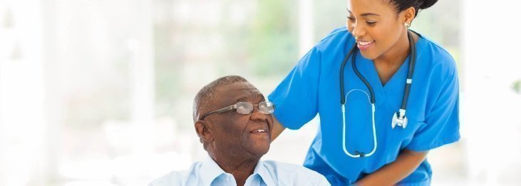Enfermera sonriendo y conversando con un paciente mayor.