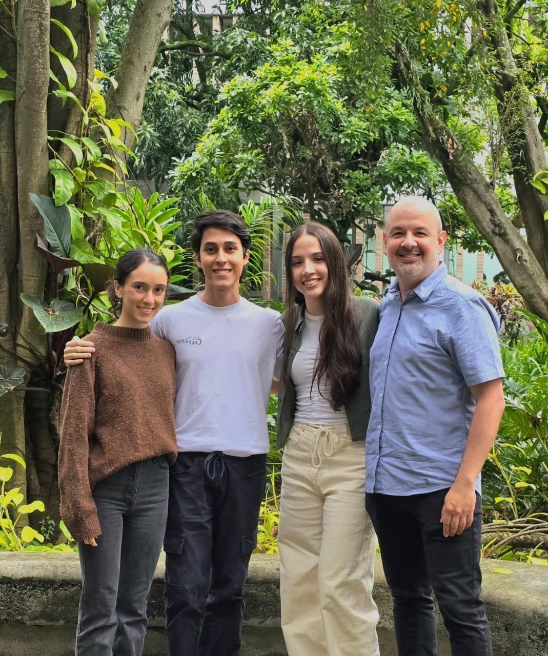 Tres estudiantes de la Facultad de Arquitectura de la Universidad Pontificia Bolivariana, junto con el profesor Lucas Arango Díaz, posan en un espacio verde del campus tras obtener el primer lugar en la fase nacional del Concurso Saint-Gobain